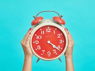 Twee handen met ouderwetse wekker met bellen